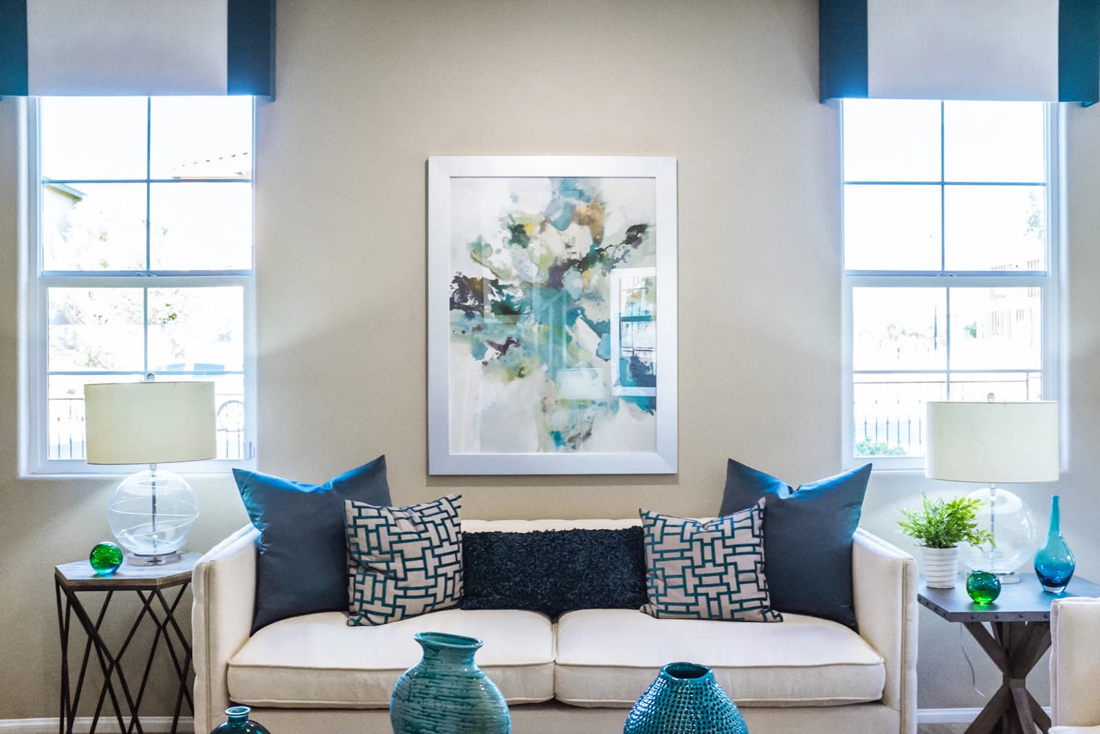 A classic lounge with a white sofa, navy cushions and tall shuttered windows