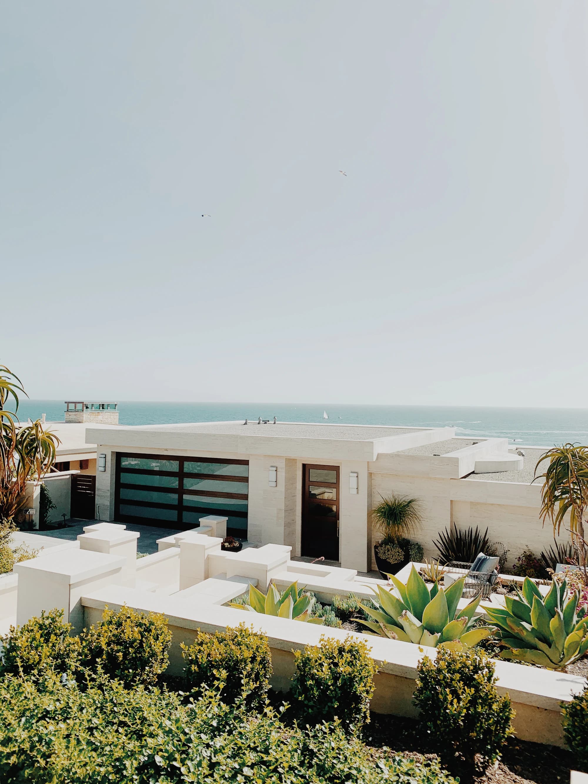 A low white house on the coast with the sea beyond its roofline